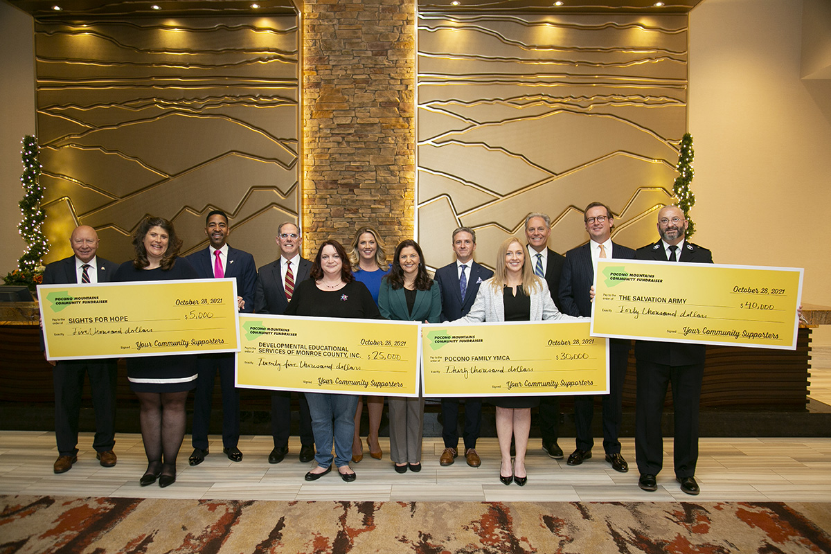 Group of previous check recipients holding large checks